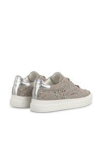 Zapatillas de ante beige con acentos plateados, detalles de tachuelas y una superficie texturizada. Suelas de goma blanca con un branding mínimo.
