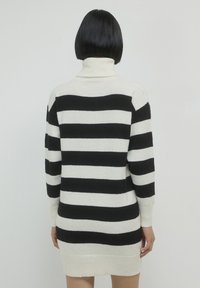 Abito a maglia a righe nero e crema con collo alto e polsini a costine, caratterizzato da ampie righe orizzontali e una morbida trama in maglia.