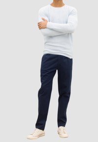 Camisa de manga larga azul claro, pantalones marinos, zapatillas neutras con cordones. Diseño simple y ajustado con textura suave. Sin patrones ni acentos visibles.