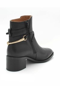 Czarne skórzane botki za kostkę z okrągłym noskiem, niskim blokowym obcasem, bocznym zamkiem błyskawicznym oraz złotym akcentem z tyłu. Gładka tekstura na całej powierzchni.