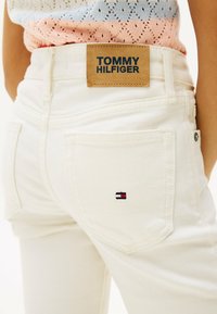 Weiße Jeans aus Denim mit einem Tommy Hilfiger Lederpatch am Bund und einem kleinen gestickten Logo in Rot, Weiß und Blau auf der Gesäßtasche.
