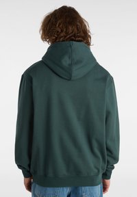 Felpa verde, in misto cotone, con un ampio cappuccio e polsini a coste, caratterizzata da una texture liscia e una vestibilità comoda. Nessun marchio o motivo visibile.