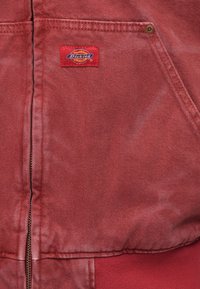 Κόκκινο τζιν μπουφάν με μπροστινό φερμουάρ, υφή υφάσματος και κεντημένο λογότυπο Dickies στην τσέπη του στήθους.