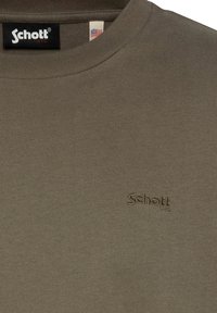 Sweatshirt en coton vert olive avec un col rond côtelé et un logo "Schott" brodé dans le même fil. Texture lisse, coupe classique.