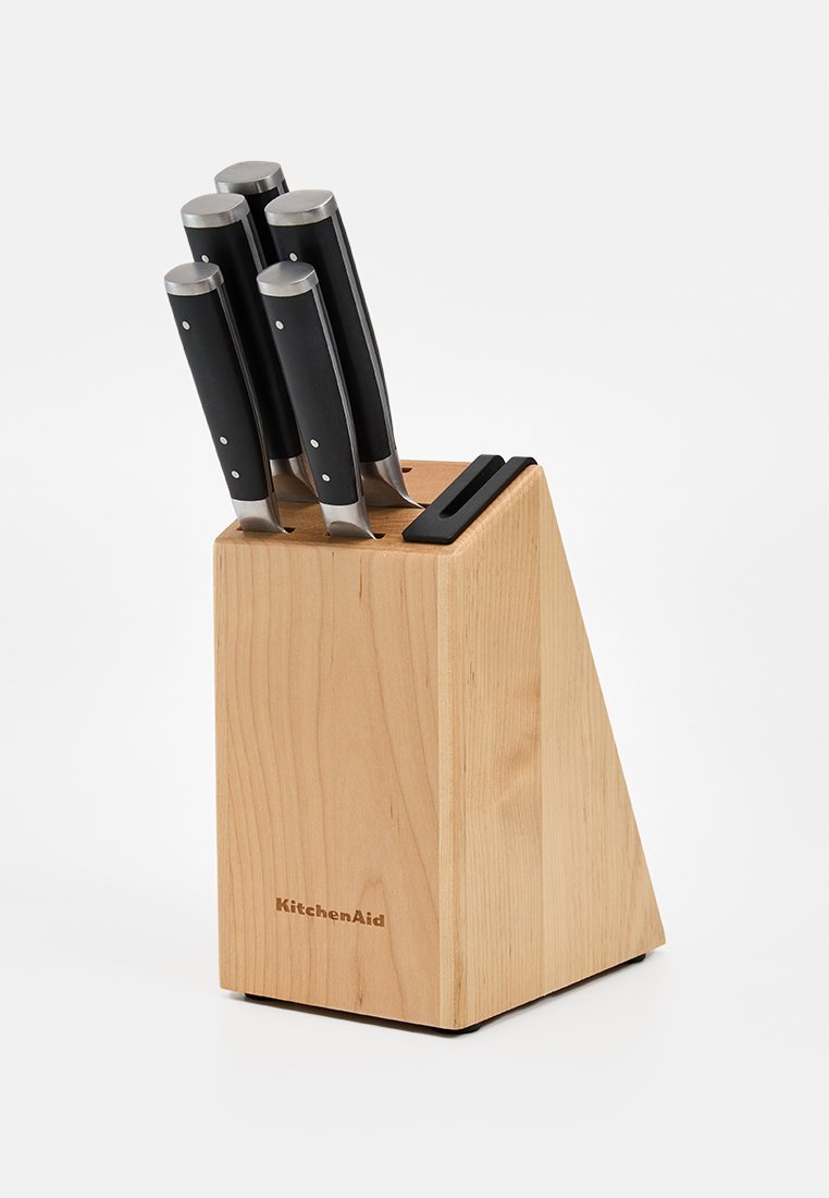 Bloc à couteaux en bois KitchenAid contenant cinq couteaux de cuisine à manches noirs, posé sur un fond blanc.