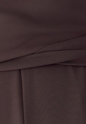 Zbliżenie złożonej ciemnobrązowej tkaniny z delikatną skośną fakturą prążkowaną i widocznym przeszyciem.