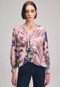 Blouse florale avec col et manches volantés dans des teintes de rose, bleu et vert. Tissu doux et léger avec une coupe décontractée.