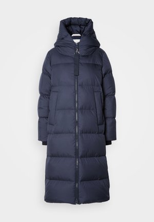 Veste en duvet marine, mi-longue avec une capuche, dotée d'une fermeture éclair à l'avant, de grandes poches et d'une texture matelassée. Matériau doux et isolé.