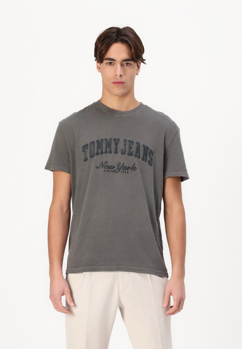 Camiseta de algodón gris con el texto "TOMMY JEANS New York" en un contraste azul oscuro. Cuello redondo y mangas cortas.