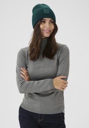 Suéter gris de cuello alto hecho de una tela suave y gruesa con mangas largas. Combinado con un gorro de punto acanalado verde oscuro.
