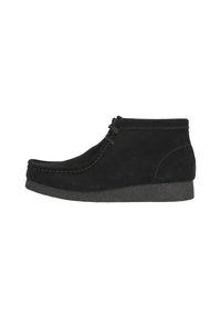 Botines de ante negro con punta redonda, detalles de costura y suela de goma. Presentan un diseño con cordones y un acabado texturizado.