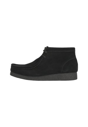 Botines de ante negro con punta redonda, detalles de costura y suela de goma. Presentan un diseño con cordones y un acabado texturizado.