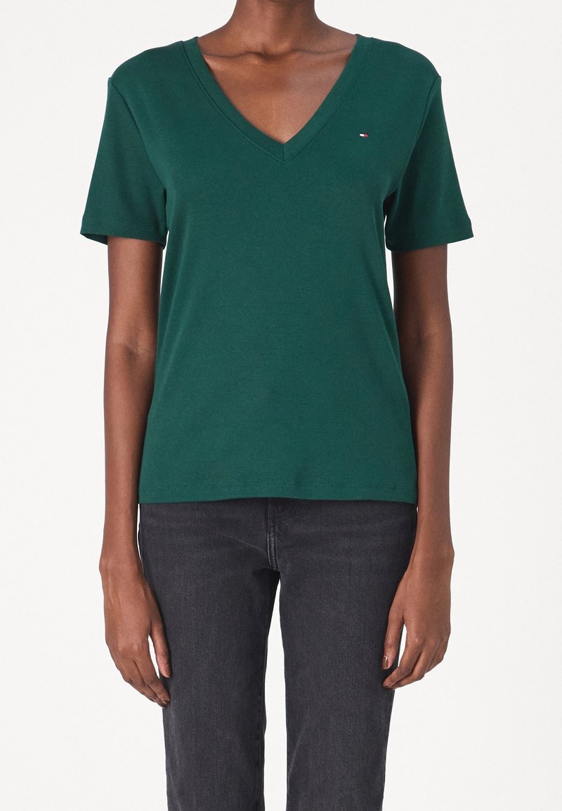 Grön bomullst-shirt med kort ärm och V-ringning som har en liten logotyp på vänster bröst och en klassisk passform. Slät textur och enkelt design.