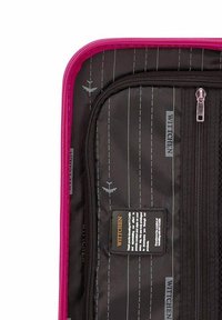Interno della valigia nero con cerniera rosa. Presenta un motivo a righe, motivi aerei e un'etichetta con testo. Sono presenti due scomparti con zip.
