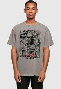 Gray oversized T-shirt featuring a comic-style graphic print with text and characters in black and red, showcasing a bold design and casual fit.