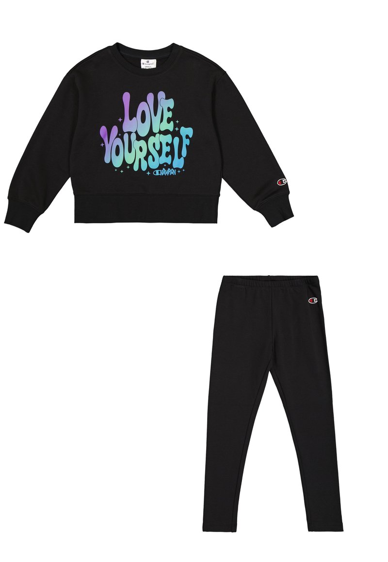 Sudadera corta negra con el gráfico "Ámate a ti mismo" en colores pastel; combinada con leggings negros. Ambos presentan detalles del logo de Champion.