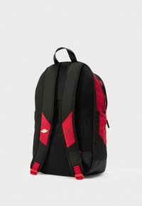 Μαύρο και κόκκινο σακίδιο με επενδυμένους ιμάντες ώμου, επάνω λαβή, πλαϊνές τσέπες και μικρά ασημί και σκούρα λογότυπα στους ιμάντες.