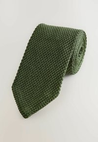 Masywowy krawat w ciemnozielonym kolorze, charakteryzujący się teksturowanym wykończeniem i ukośnym końcem. Rolowane wzornictwo podkreśla pleciony materiał i jednolitą barwę.