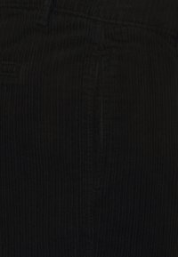 Μαύρο κοτλέ ύφασμα με κατακόρυφες ραβδώσεις, �που παρουσιάζει μια λεία, υφαντή επιφάνεια. Διαθέτει πλαϊνή τσέπη και ζώνη.