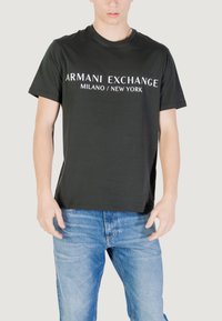 T-shirt in cotone nero con la scritta "ARMANI EXCHANGE MILANO / NEW YORK" in lettere bianche in grassetto sulla parte anteriore. Maniche corte.