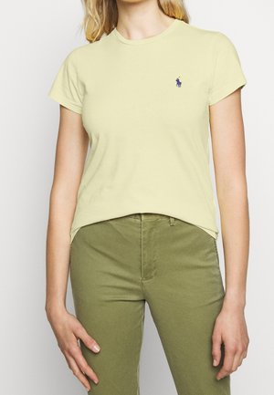 T-shirt en coton jaune clair avec un col rond et des manches courtes. Présente un petit logo brodé bleu sur la poitrine gauche.