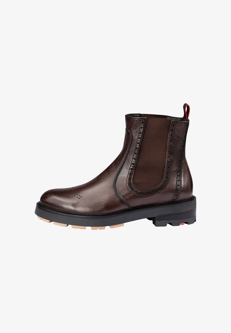 Brown leather ankle boot with elastic side panels, decorative perforations, contrasting black rubber sole, and red pull tab at the back.