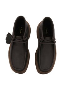 Un paio di scarpe Clarks in pelle marrone scuro con punta arrotondata, design con lacci e suole in gomma marrone chiaro, viste dall'alto.