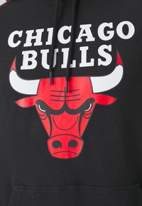 Felpa nera con cappuccio caratterizzata da un prominente logo rosso dei Chicago Bulls con la testa di un toro stilizzata, testo bianco sopra che recita "CHICAGO BULLS" e cordini.
