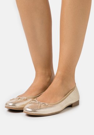 Bailarinas metálicas doradas con un acabado texturizado, que presentan un pequeño lazo decorativo y un tacón bajo y redondeado. Suave forro interior.