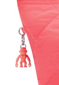 Zaino trapuntato in tessuto corallo brillante con una superficie liscia. Presenta un portachiavi a forma tonda con una piccola figura rosa attaccata da un anello metallico.
