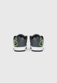 Černé a šedé tenisky s jasně zelenými akcenty. Mají polstrovaný límec, texturovanou vrstvu a bílou gumovou podrážku. Vzorované logo na bocích.