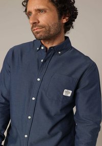 Marineblauwe knoopshirt in een katoenmix, met een borstzak met een wit label, een button-down kraag en witte knopen.