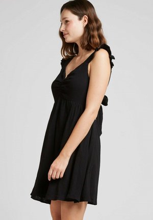 Robe noire avec un corsage ajusté, des bretelles volantes et une jupe évasée. Confectionnée en tissu léger, elle présente un décolleté en V et des fronces à l'avant.