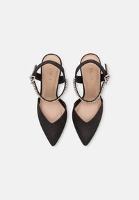 Scarpe slingback nere a punta, realizzate in tessuto testurizzato, con una sottile cinghia alla caviglia decorata con piccoli dettagli metallici.