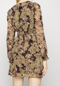 Kleid mit Blumenmuster, langen Ärmeln und einem gesmokten Bund. Die Farben sind Grün, Burgunderrot und Braun, mit Rüschendetails.