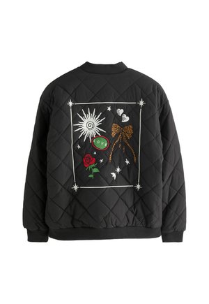 Černá prošívaná bunda se vzorem výšivky na zádech – slunce, mašle s leopardím vzorem, červená růže, dvě srdce, hvězdy a zelená nášivka „LOVE“ uvnitř bílého obrysu.