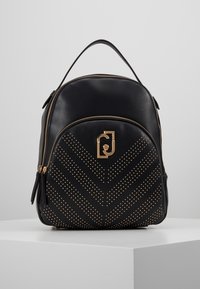 Mochila de cuero negro con un patrón de chevron de tachuelas doradas, herrajes dorados, un asa en la parte superior y un compartimento principal con cremallera.