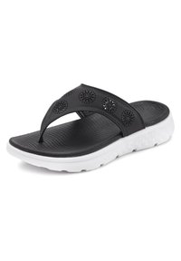Musta flip-flop sandaali, jossa on rei'itetty päällinen, uriteltu pohja ja valkoinen synteettinen pohja, jossa on geometrinen kuosi.