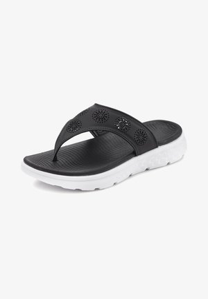 Čierne šľapky s perforovaným vrchným dizajnom, textúrovanou stielkou a bielou syntetickou podrážkou s geometrickým vzorom.