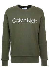 Felpa verde oliva con girocollo, polsini a coste e un grande logo bianco "Calvin Klein" sul petto. Tessuto morbido.