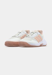 Coppia di sneakers sportive bianche e rosa chiaro con suole strutturate e design con lacci, posizionate affiancate su sfondo bianco.