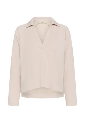 Haut beige clair à manches longues avec col et décolleté en V profond, ourlet légèrement court, et coupe décontractée.