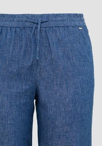 Blauwe denim joggers met een elastische tailleband en veters. Glad textuur met subtiele verticale patroon details. Inclusief een klein merkteken accent.