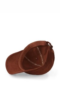 Casquette en velours côtelé marron avec une visière structurée, des détails cousus et une doublure intérieure contrastante. Elle est dotée d'une fermeture éclair et d'un ruban logo à l'intérieur.