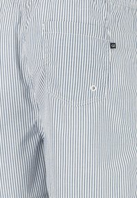 Randiga shorts i ljusblått och vitt, med en bakficka och en liten svart etikett. Tillverkade av lättviktig tyg med en slät yta.