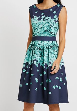 Ärmelloses marineblaues Midikleid mit grünem Blumenblättermuster, das sich um das Oberteil und den Rock konzentriert, mit tailliertem Schnitt und plissiertem Rock.