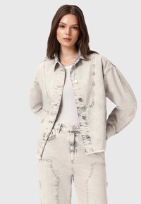 Jasnoszara kurtka dżinsowa o luźnym kroju, z zapięciem na guziki i oversize'owymi rękawami. Posiada widoczne szwy i wyblakłą teksturę.