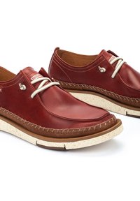 Chaussures en cuir rouge avec un bout arrondi, des coutures contrastantes en beige et une semelle légère moirée. Caractéristiques d'une boucle à lacet décorative en argent.