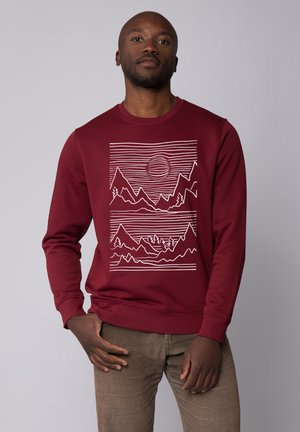 Burgundy sweatshirt with a graphic design featuring mountains and sun in white lines. Long sleeves and ribbed cuffs. Smooth texture.