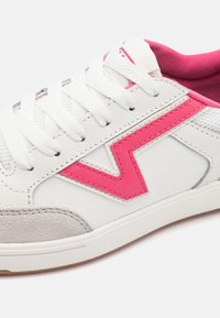 Białe trampki z różowymi skórzanymi akcentami, teksturowanym szarym zamszowym noskiem i szarymi meshowymi panelami. Płaskie sznurówki i gumowa podeszwa.